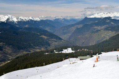 Fransa 'nın Üç Vadisi' ndeki popüler kayak merkezi Meribel 'den bir dağ vadisi manzarası. Kayakçılar ve snowboardcular soluk kesen Fransız Alp Dağları 'nın arka planında piste çıkıyorlar..