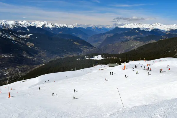 Fransa 'nın Üç Vadisi' ndeki popüler kayak merkezi Meribel 'den bir dağ vadisi manzarası. Kayakçılar ve snowboardcular soluk kesen Fransız Alp Dağları 'nın arka planında piste çıkıyorlar..