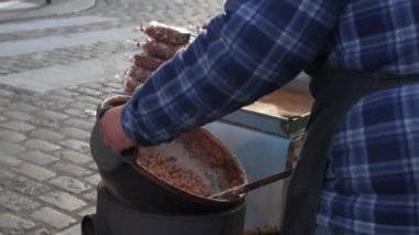 Açık hava pazarında sıcak fındık yiyen bir adam. Paris, Fransa 'da karamelli fındık pazarında satmak için sıcak şekerli badem karıştıran bir sokak satıcısı..