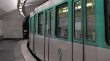 Paris, Fransa - 6 Aralık 2024: Paris metro sistemindeki metro istasyonu. Tren bir yeraltı istasyonuna varıyor ve insanlar platforma biniyor..