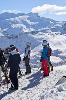 Meribel, Fransa - 13 Mart 2024: Fransa 'nın Üç Vadisi' ndeki Meribel kayak merkezinin tepesindeki dağ manzarasına bakan kayakçılar ve snowboardcular grubu.