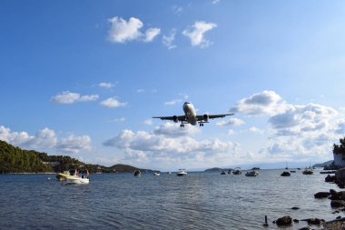 Ticari uçak Yunanistan 'ın Skiathos Uluslararası Havaalanı limanına inmek üzere iniyor. Alçak uçan uçak küçük balıkçı teknelerinin üzerinden suya yakın seyahat eder. Yunanistan 'da aydınlık yaz günü