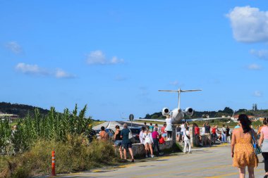 Skiathos, Yunanistan - 5 Eylül 2022: Skiathos havaalanı pistinin sonunda bir grup insan uçak tespit etti. Kısa pist limanın kenarında duruyor, yayalar uçağın kalkışını izliyor.