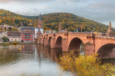 Bulutlu bir günün erken saatlerinde Karl Theodor Köprüsü (Almanca: Karl-Theodor-Brcke) ve Alman şehri Heidelberg 'in eski kapısı görülebilir. Heidelberg Neckar Nehri 'nde.