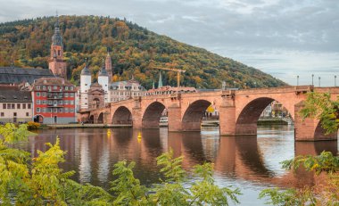 Bulutlu bir günün erken saatlerinde Karl Theodor Köprüsü (Almanca: Karl-Theodor-Brcke) ve Alman şehri Heidelberg 'in eski kapısı görülebilir. Heidelberg Neckar Nehri 'nde.