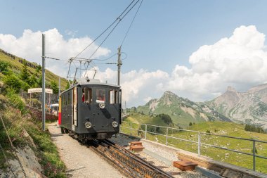 İsviçre Alpleri 'ndeki Schynige Platte tren istasyonunda eski çarklar. Dağ tren istasyonunda eski vagonları olan klasik siyah bir lokomotif. 10 Temmuz 2023, Schynige Platte, İsviçre