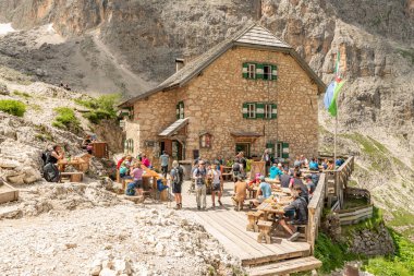 Langkofelhtte (Rigugio Vicenza) mountain hut during summer with impressive dolomites in the background. Hiking tourists on the terras. World heritage site. 14 july 2024, Val gardena, Italy clipart