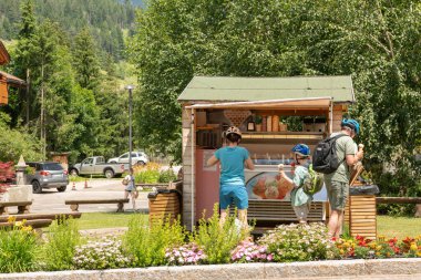 Kafkasyalı turistler bir sokak satıcısının önünde dondurma yiyorlar. İtalyan Dolomitleri 'nde yaz zamanı. Pozza Di Fassa, Val di fassa, İtalya, 15 Temmuz 2024