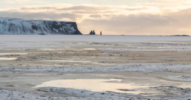 Öğleden sonra manzarası, Reynisfjara sahilinde sıcak sarı ışık ve gökyüzü ve İzlanda 'nın güney kıyılarında, deniz yığınları. Buz ve kar, uzak bir yer. Harika bir doğa..