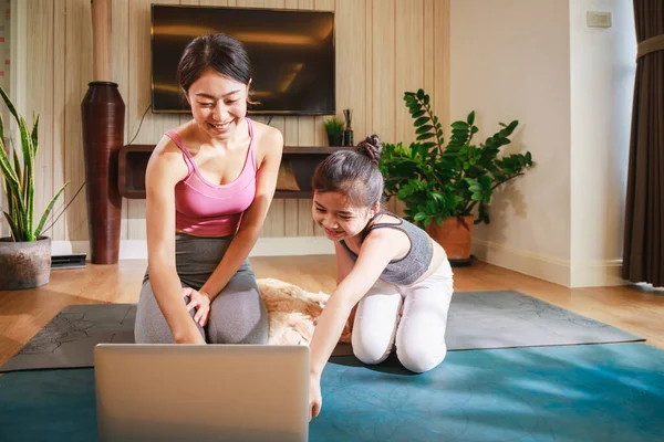 アジアの女性と娘は自宅でラップトップを介してヨガオンラインコースからヨガを練習 — ストック写真