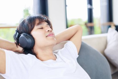 Evde dinlenen, Adam rahat bir koltukta müzikten zevk alıyor.