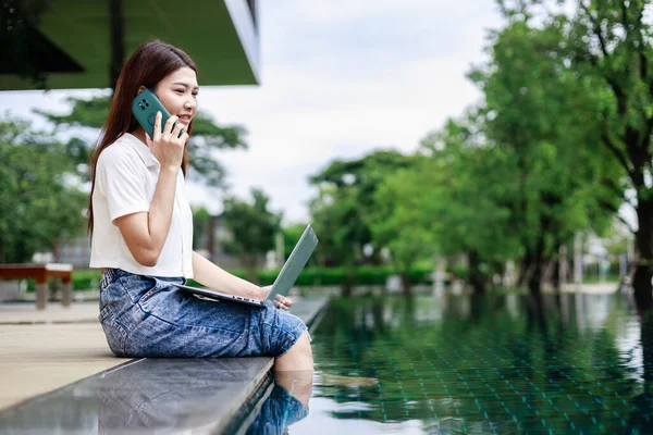Vacation Mode, Woman Unwinds by the Pool with Smartphone in Hand at Luxurious Resort