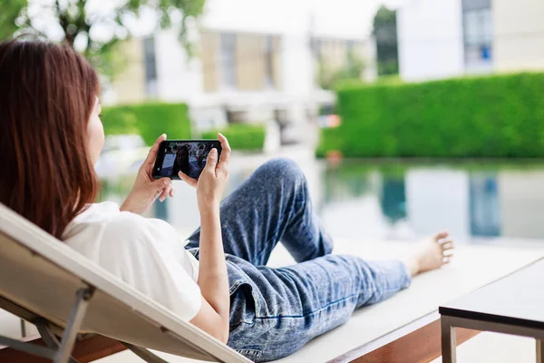 Travel Technology, Woman Uses Smartphone to Plan and Share Vacation Experiences by the Pool