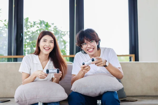 Couple playing video games together in living room, happiness and married people concept.