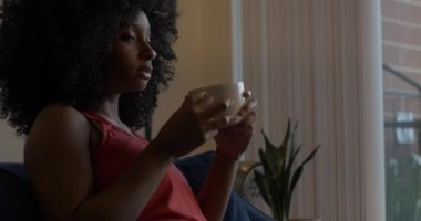 Sıcak bir kanepede fincandan kahve içmek.