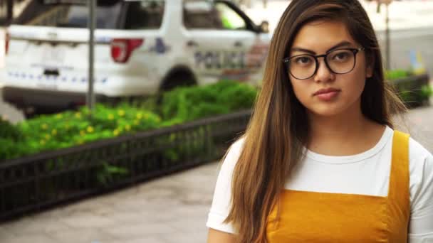 Молода Жінка Меншості Нейтральною Експресією Перед Поліцейською Машиною — стокове відео