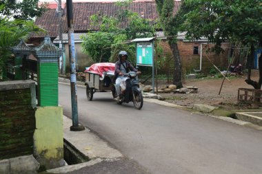 Tekerlekli sandalyedeki yaşlı adam sokakta sırt çantası taşıyor.