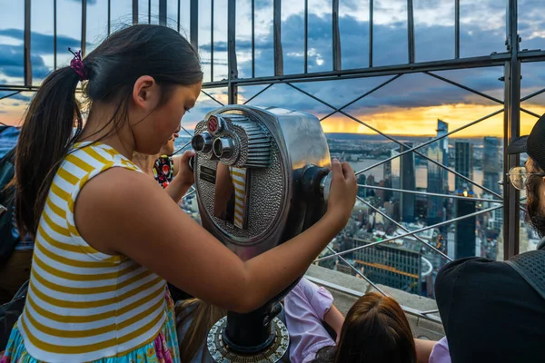 New York, ABD, Ağustos 2022 - Küçük bir Asyalı kız Empire State binasının gözetleme noktasında dürbün kullanıyor