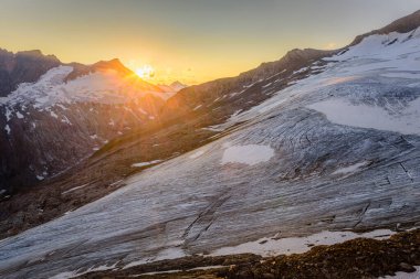 Avusturya 'daki High Tauern Ulusal Parkı' nda, Mullwitzkees buzulunun üzerinde batan güneş..