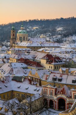 Mala Strana ve St. Nicholas Kilisesi Prag 'ın eski bir kasabasında kış sabahı karla kaplandılar..