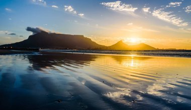 Lagoon sahilinden Cape Town 'daki Masa Dağı' nın üzerinde güzel bir günbatımı. 