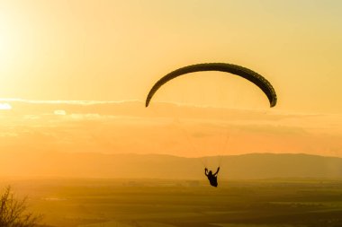 Gün batımında yamaç paraşütü yapan bir adam.. 