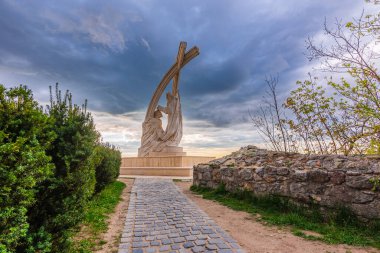 Esztergom 'daki kireçtaşı heykel, Tuna' ya bakan ve Pannonhalma 'lı Aziz Astrik tarafından taçlandırılan Kral Stephen' ın iki katı büyüklüğünde. Bütün, üzerinde haç olan iki kavisin altında..