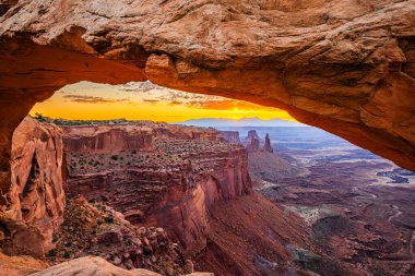Utah 'ta Moab yakınlarındaki Kanyonlar Ulusal Parkı' nın Gök Bölgesi 'ndeki Mesa Kemeri' nde renkli bir sabah güneşi doğuyor..