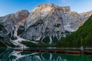 İtalyan Alpleri 'ndeki Lago di Braies veya Pragser Wildsee Dolomitleri sabahın erken saatlerinde yansıma ve ahşap teknelerle şafak vakti.