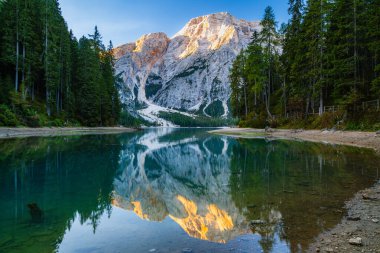 İtalyan Alpleri 'ndeki Lago di Braies veya Pragser Wildsee Dolomitleri sabahın erken saatlerinde yansıma ve ahşap teknelerle şafak vakti.