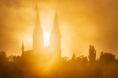 Vysehrad Bazilikası sabahın erken saatlerinde güneşli sis ve sonbaharda gündoğumunda UNESCO şehir sitesi Prag 'da bulutlar.