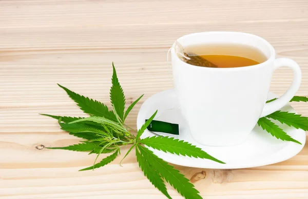 Kenevir çantalı beyaz bardak, kenevir yaprakları ahşap masa üzerinde, boşluk kopyala