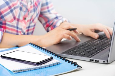 Modern işyeri. Belgeler, notlar ve beyaz masada boş ekranlı akıllı telefon, dizüstü bilgisayar kullanan kadın. Ev konseptinde çalışmak