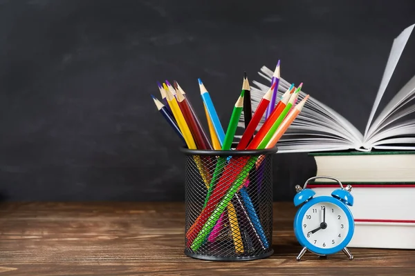 Tahta arka planda kitap, kalem ve saat yığınına karşı ahşap masa, boşluğu kopyala