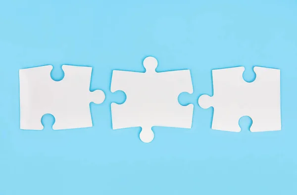 Three empty white matching puzzle pieces on blue background