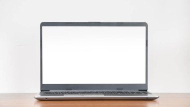 Boş tahta masa üzerinde boş ekranlı dizüstü bilgisayar beyaz duvar arkaplanı, kopyalama alanı, modern minimalist iç mekan
