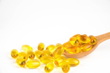 Omega 3 kapsülleri tahta kaşıkta ve beyaz arka planda.