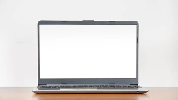 Boş tahta masa üzerinde boş ekranlı dizüstü bilgisayar beyaz duvar arkaplanı, kopyalama alanı, modern minimalist iç mekan