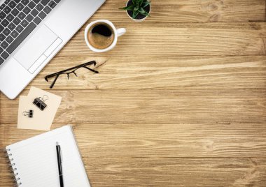 Fotokopi alanı olan işyeri. Dizüstü bilgisayar, kahve, not defteri ve bardaklar ahşap masada.