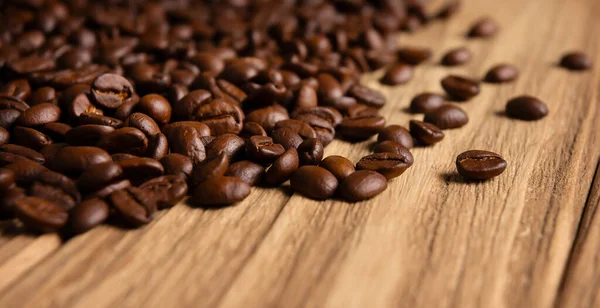 Ahşap arka planda kavrulmuş kahve çekirdekleri yakın plan.