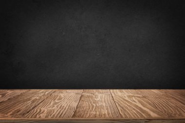 Siyah duvar arkaplanı olan kaba ahşap bir masa.