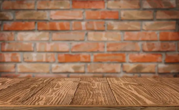 Ürün sergilemek için arka plan olarak eski tuğla duvara karşı ahşap masa