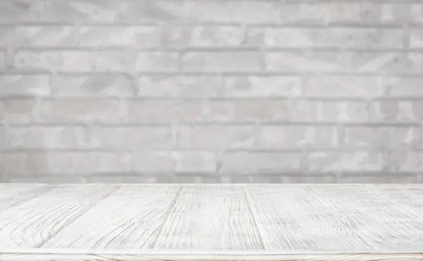 Ürün gösterisi için gri tuğla duvara karşı beyaz tahta masa