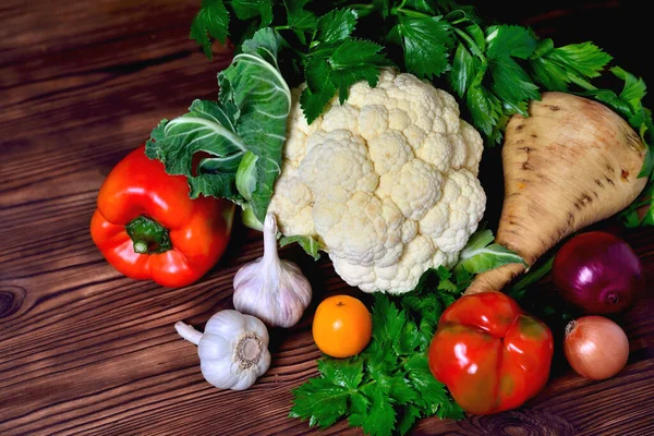 Vegetables cauliflower, bell pepper, parsnip, onion, garlic,  tomat parsley on a wooden background