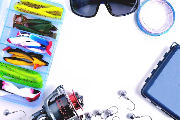 fishing accessories, box with silicone baits, fishing glasses, accessory box, fishing reel, hooks, braided fishing line on a white background, a place for copy space