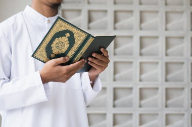 Müslüman adam Kuran okuyor. Kuran-ı Kerim 'in Arapça anlamı olan Kuran-ı Kerim