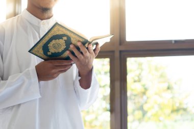 Müslüman adam Kuran okuyor. Kuran-ı Kerim 'in Arapça anlamı olan Kuran-ı Kerim
