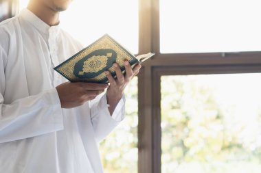 Müslüman adam Kuran okuyor. Kuran-ı Kerim 'in Arapça anlamı olan Kuran-ı Kerim