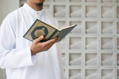 Müslüman adam Kuran okuyor. Kuran-ı Kerim 'in Arapça anlamı olan Kuran-ı Kerim