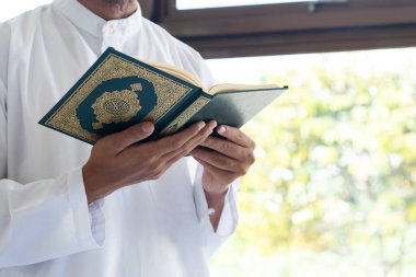Müslüman adam Kuran okuyor. Kuran-ı Kerim 'in Arapça anlamı olan Kuran-ı Kerim